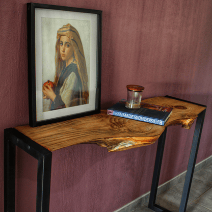 Wooden console table with framed artwork and books against a purple wall