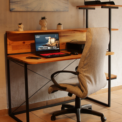 A wooden workstation desk with a laptop on it, accompanied by a chair, set against a room with a decorative wall art and a small decorative item on top of the desk.