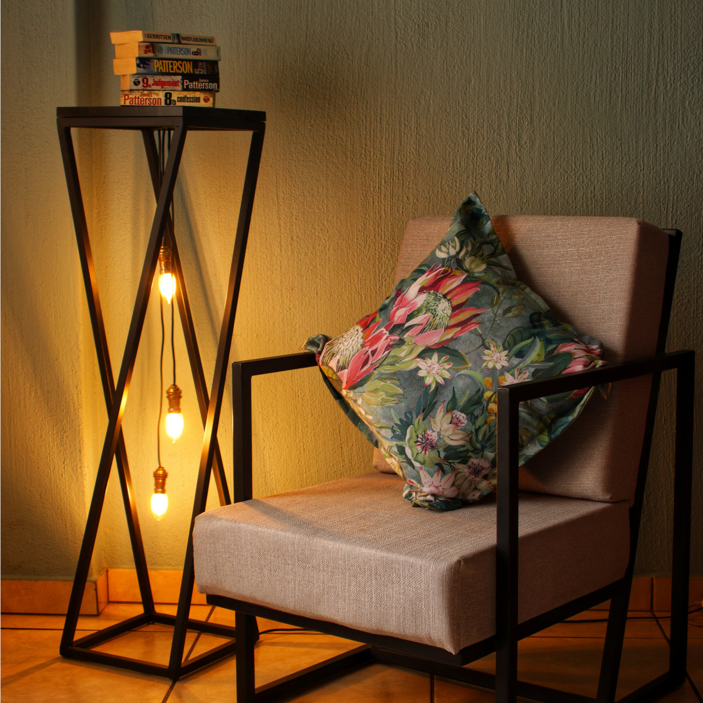 A black pendant light table with a wooden top placed next to a chair with a floral cushion, providing a warm illumination.