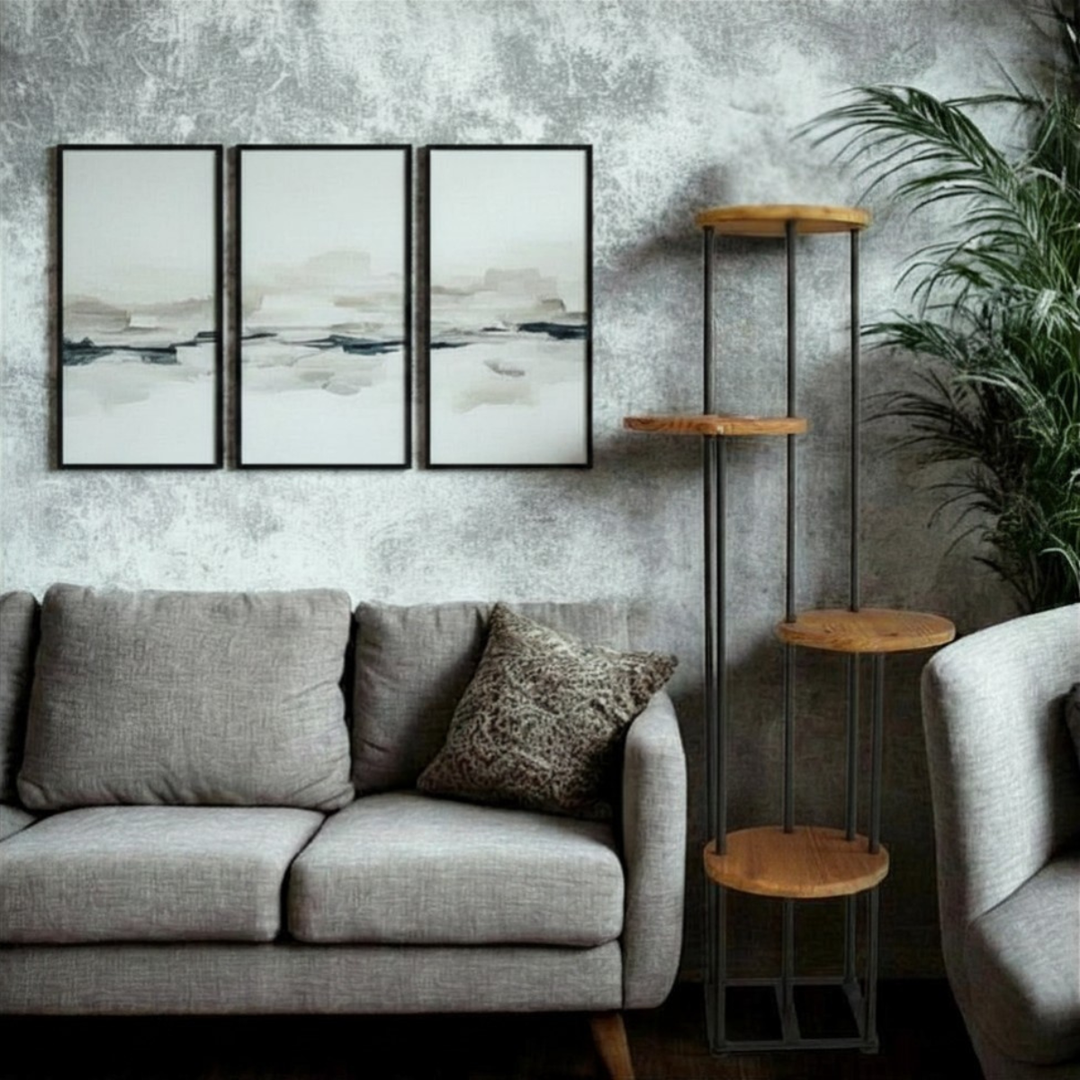 A modern living room scene featuring a three-panel abstract wall art set with a gray sofa, a tall black metal shelving unit with three wooden tiers, and a green houseplant against a textured gray wall.