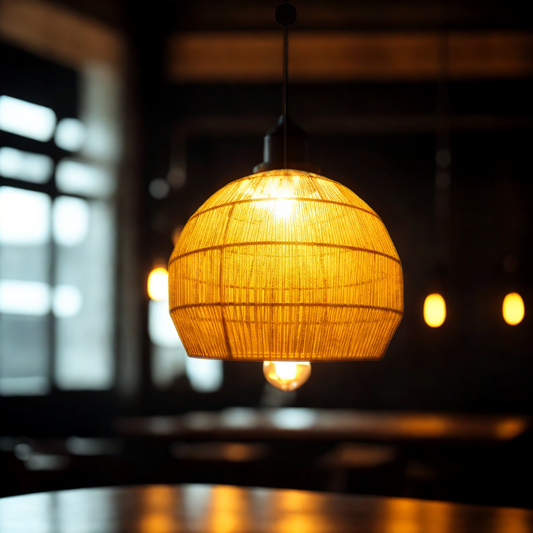 A warm, glowing large pendant light with a woven spherical shade hanging in a dimly lit, atmospheric indoor setting.