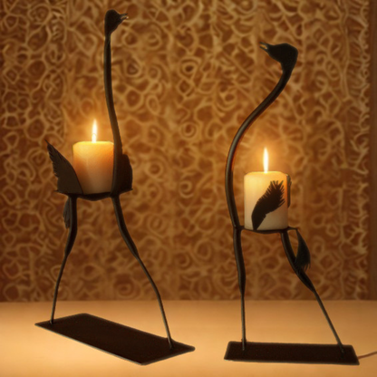 Two black metal bird-shaped candle holders with lit candles, set against a warm patterned brown background.
