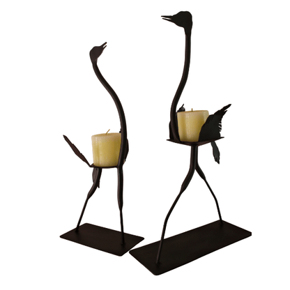 Two ostrich-shaped candle holders with candles on a white background