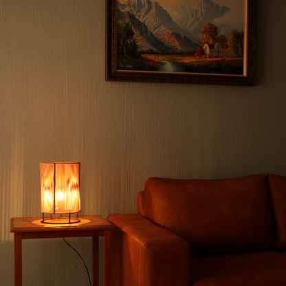 Table lamp on a wooden table next to a brown leather sofa with a painting in the background