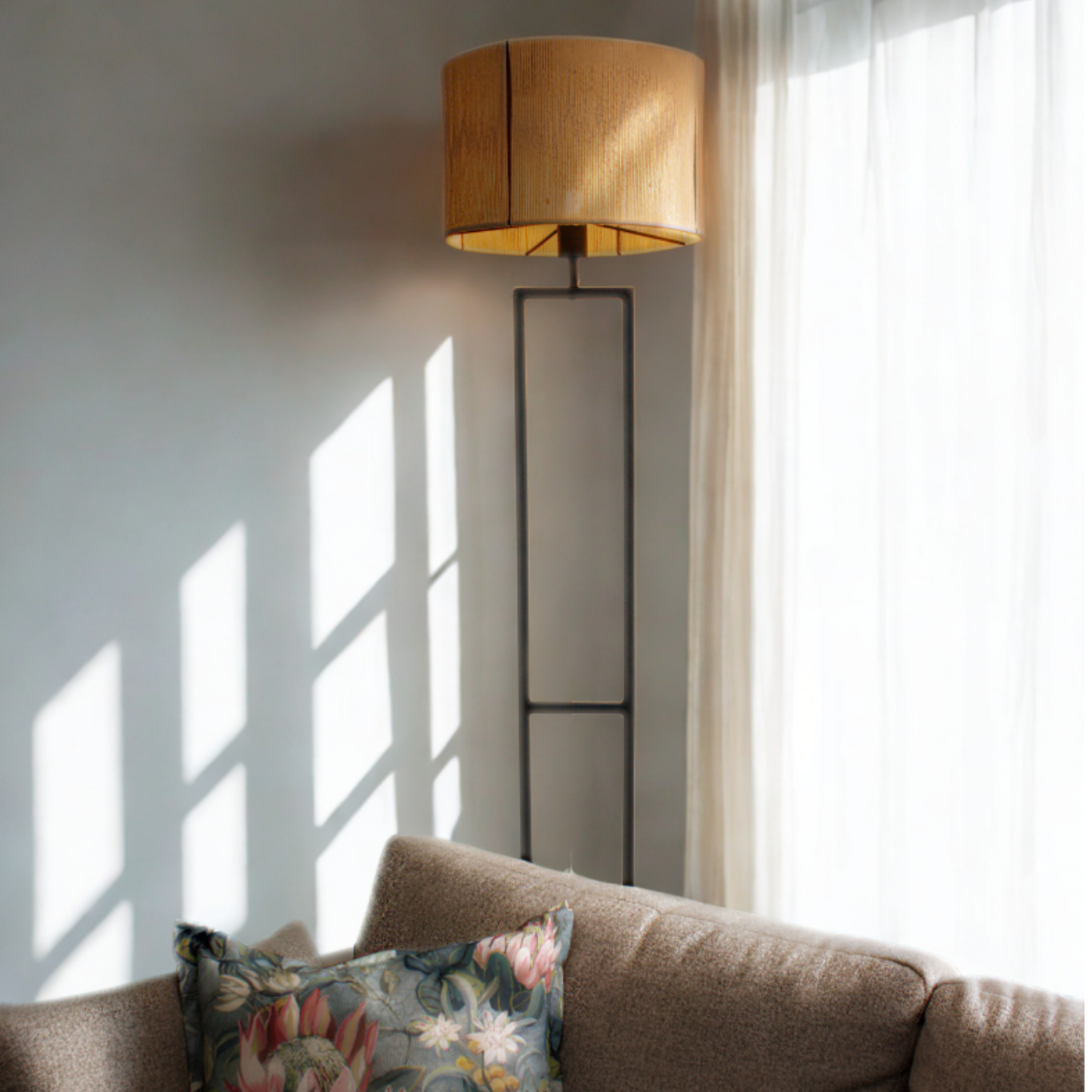 Floor lamp next to a couch with a floral pillow in a bright room