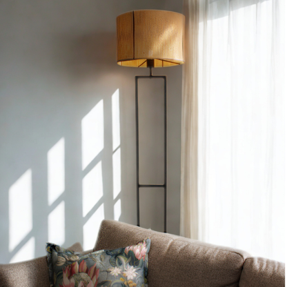 Floor lamp next to a couch with a floral pillow in a bright room