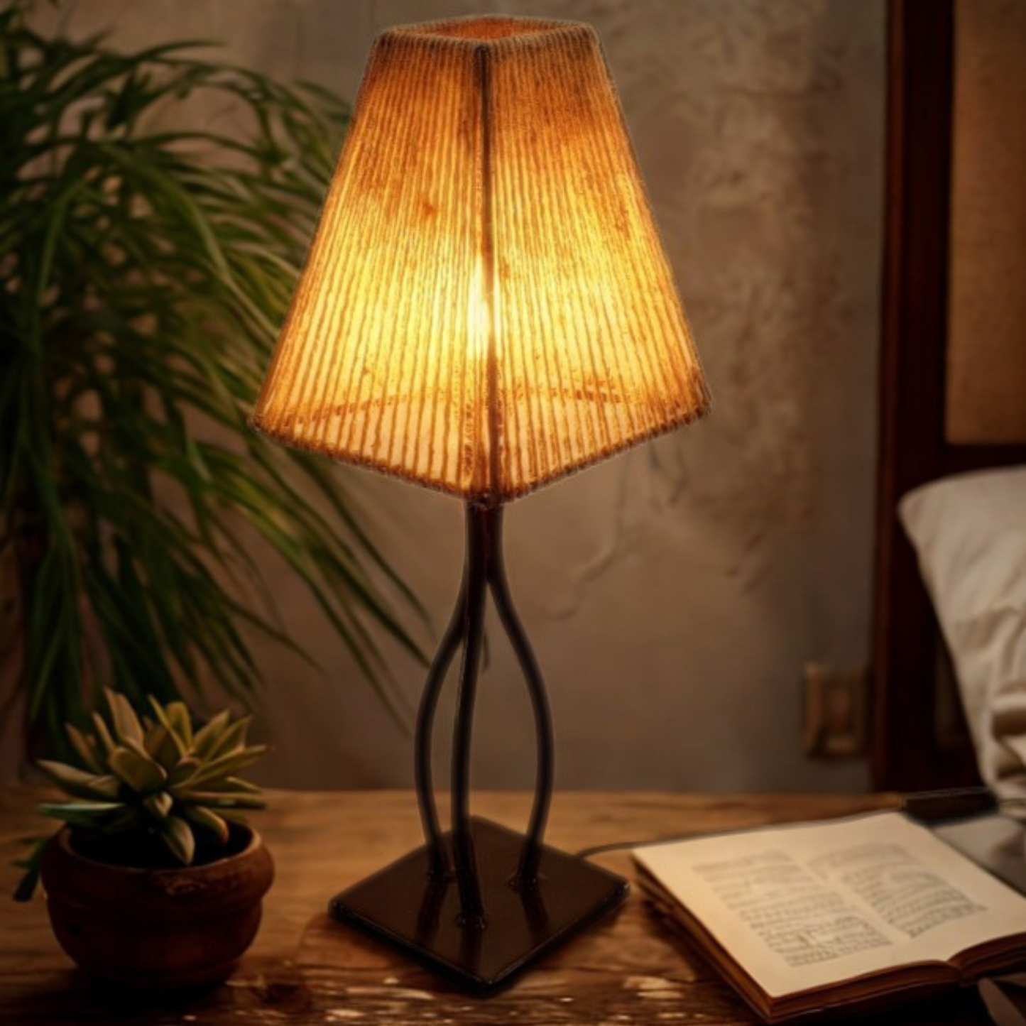 Lit side lamp on a wooden table next to a pot plant